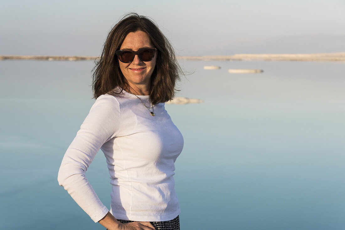 Porträt einer Frau mit Sonnenbrille und dem Toten Meer im Hintergrund; Süddistrikt, Israel.