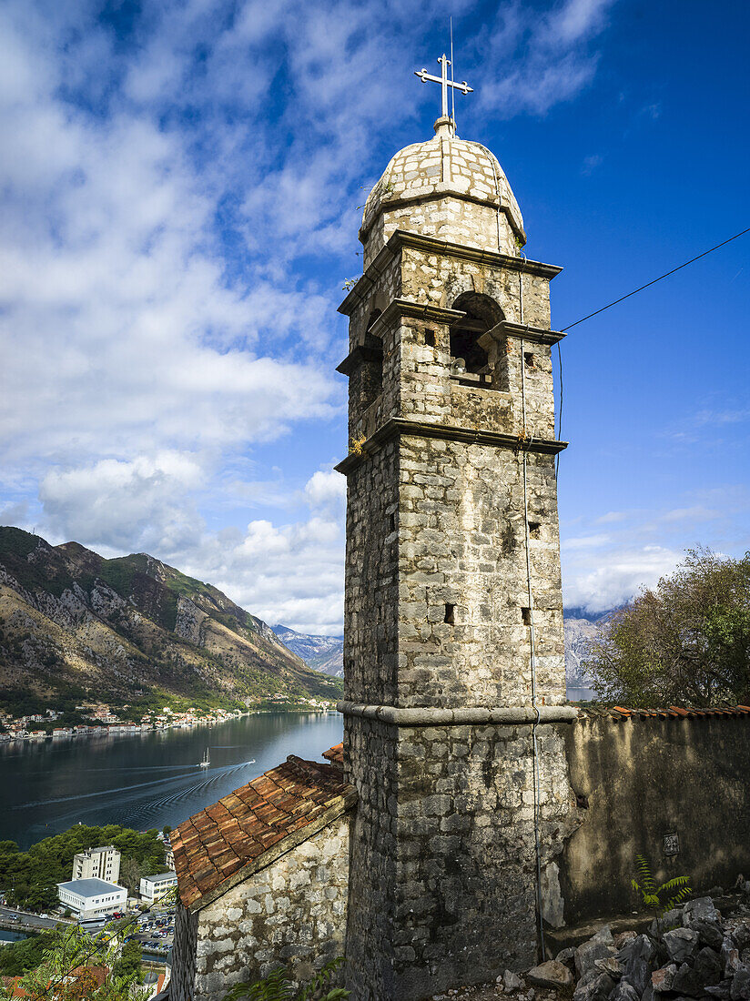 A stone tower with cross at Kotor Fortress and a view of the Gulf of Kotor; Kotor, Montenegro