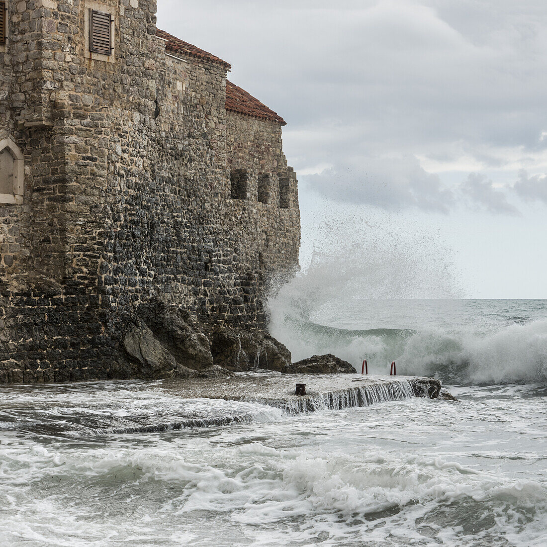 Wellen brechen und plätschern gegen die alten Steinmauern entlang der Küste von Budva; Budva, Opstina Budva, Montenegro