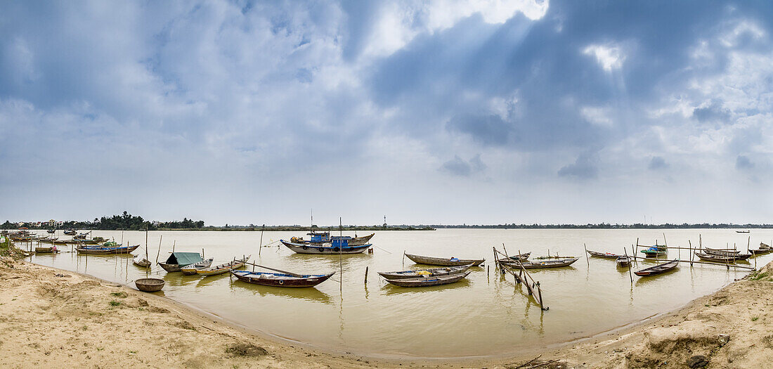 Boote, die im flachen Wasser entlang der Küste vertäut sind; Thanh pho Hoi An, Quang Nam, Vietnam.
