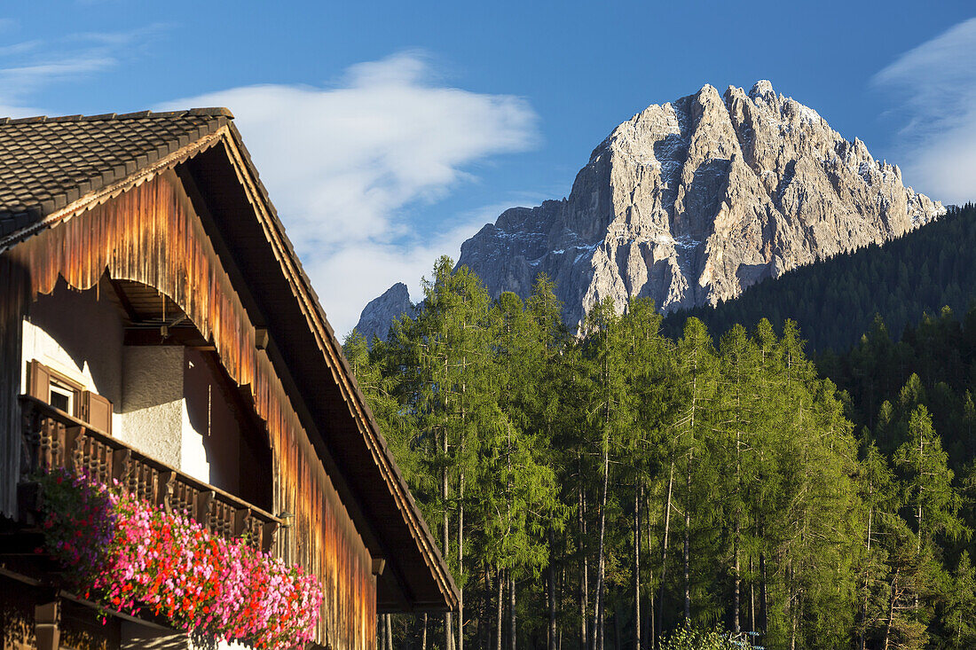 Wooden alpine chalet with flower boxes and mountain in the background with blue sky and clouds; Grainau, Bavaria, Germany