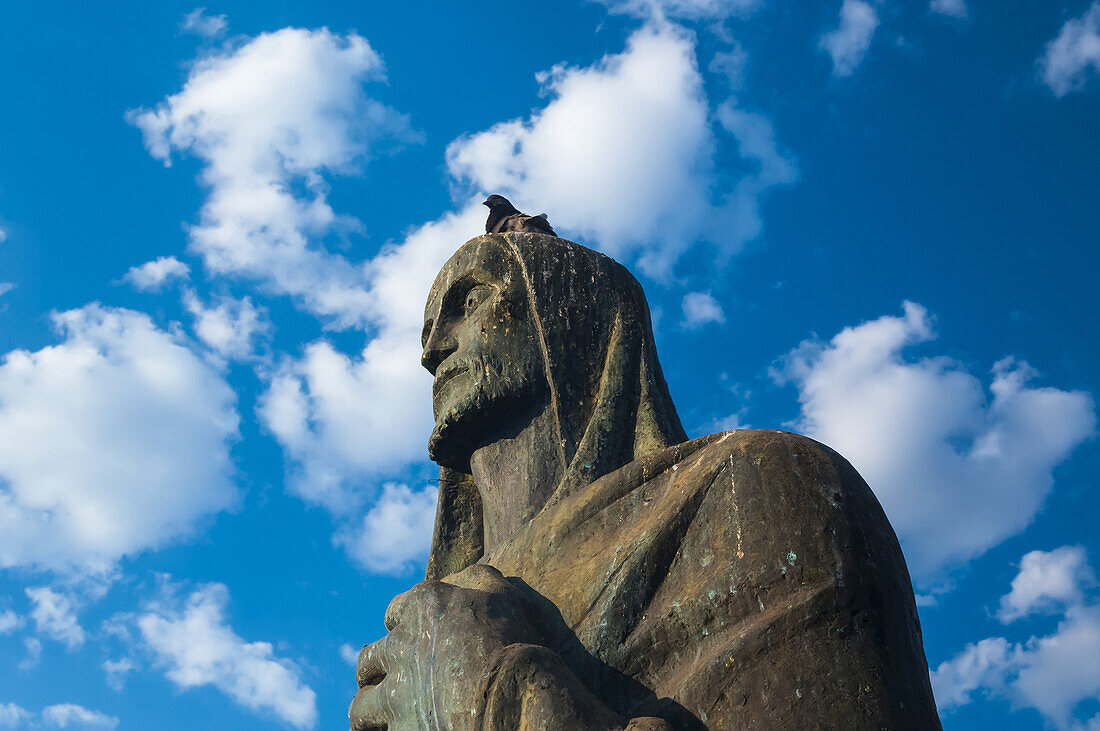 Eine Taube sitzt auf dem Kopf einer Bronzeskulptur eines Evangelisten vor der Kathedrale von Brasilia; Brasilia, Brasilien.