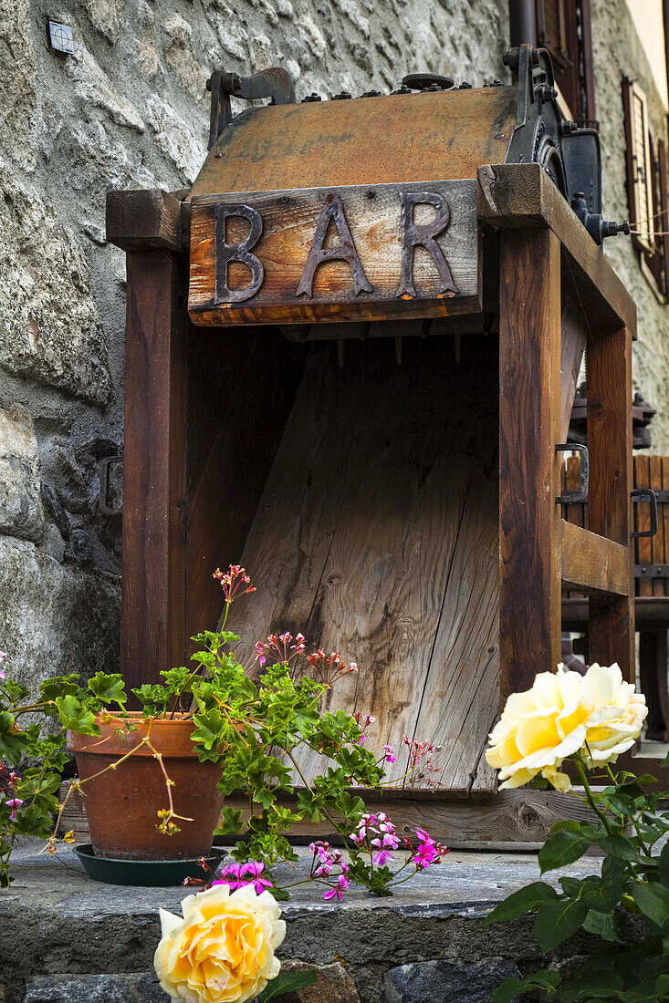 Old wooden bar equipment with flowers in pots, Dolonne, near Courmayeur; Aosta Valley, Italy