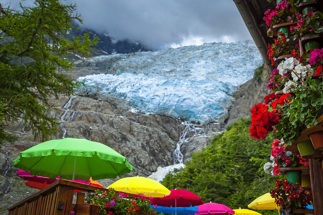 Blick auf den Bossons-Gletscher mit bunten Schirmen und Blumen vom Chalet du Glacier; Chamonix-Mont-Blanc, Haute-Savoie, Frankreich.