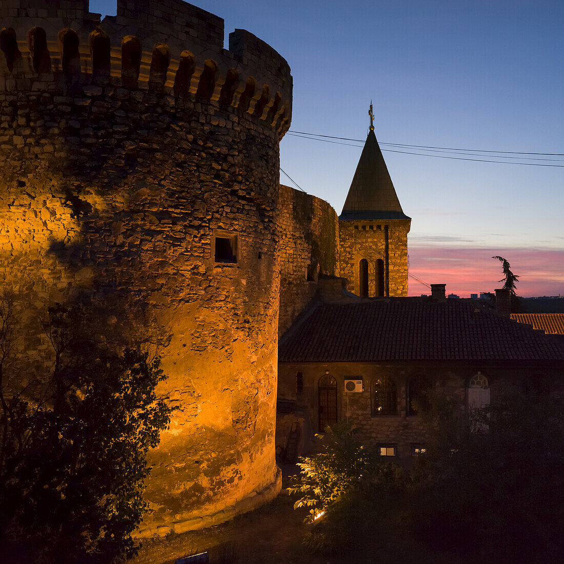 Belgrader Festung in der Abenddämmerung und die runde Steinmauer beleuchtet mit Licht und einem Turm mit Kreuz; Belgrad, Vojvodina, Serbien