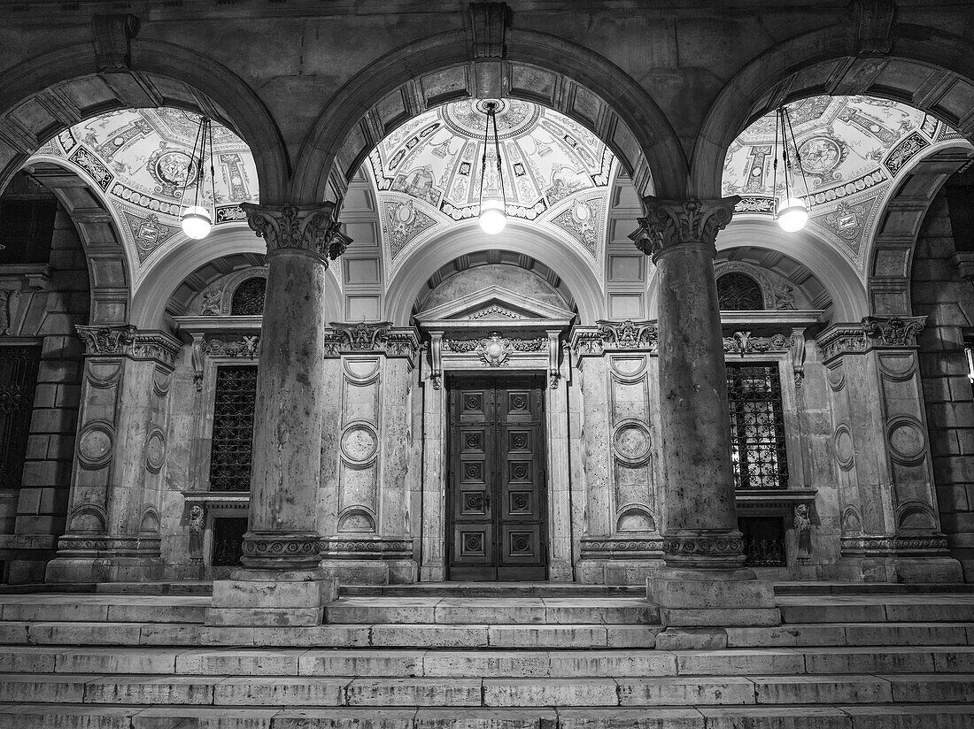 Architectural detail of a building with pillars and three domes in the ceiling with artwork and lights; Budapest, Budapest, Hungary