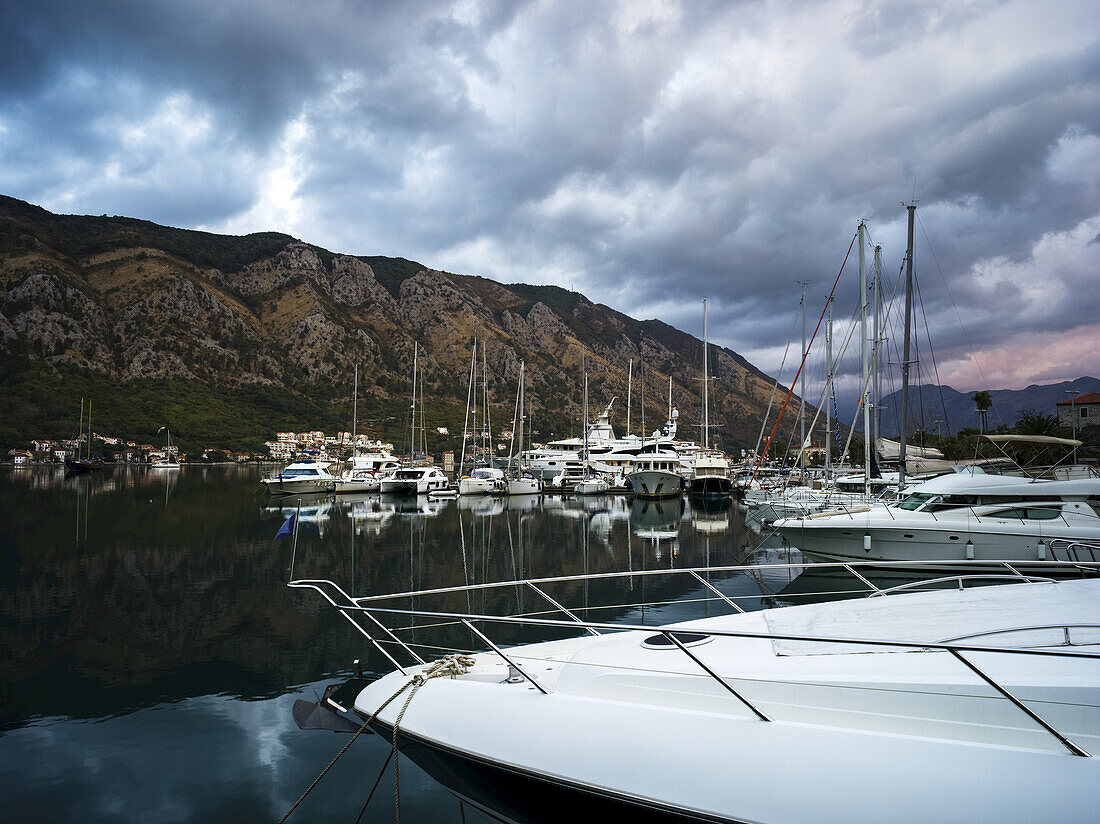 Boats moored in a tranquil harbour in the Bay of Kotor; Kotor, Montenegro