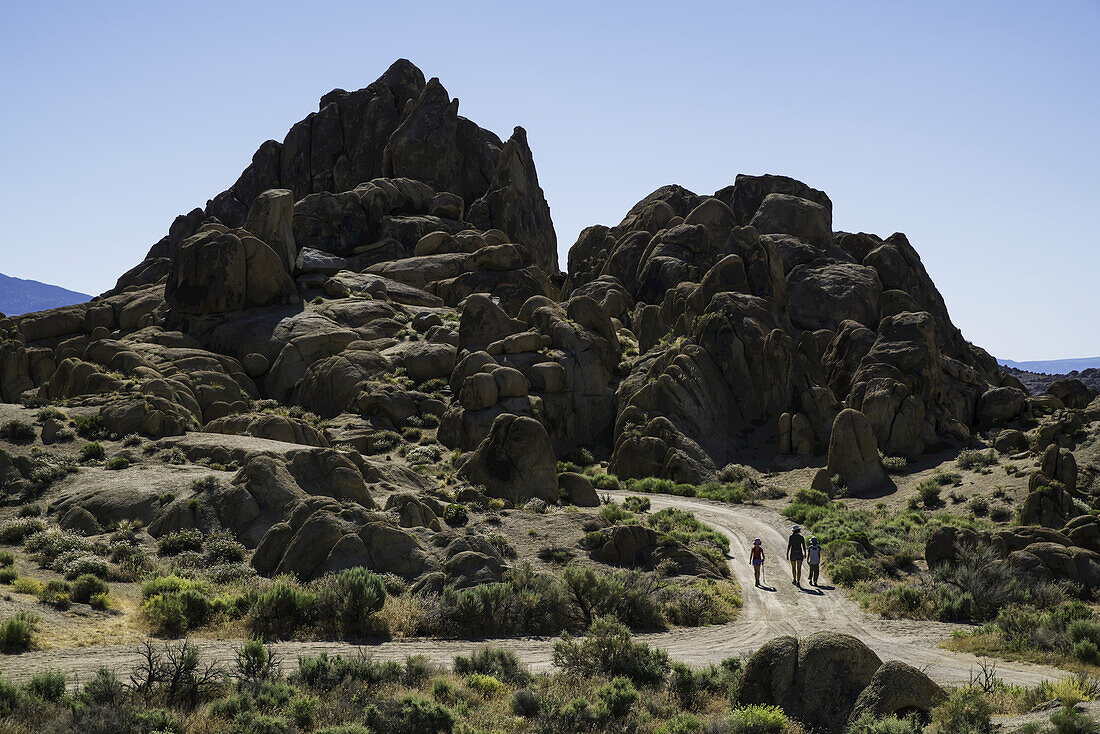 Familie geht eine Straße in den Alabama Hills entlang; Kalifornien, Vereinigte Staaten von Amerika