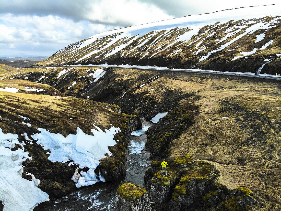 Mann beobachtet den Fluss neben der Straße in Island. Bild aufgenommen mit einer Drohne; Grundarefjorour, Island