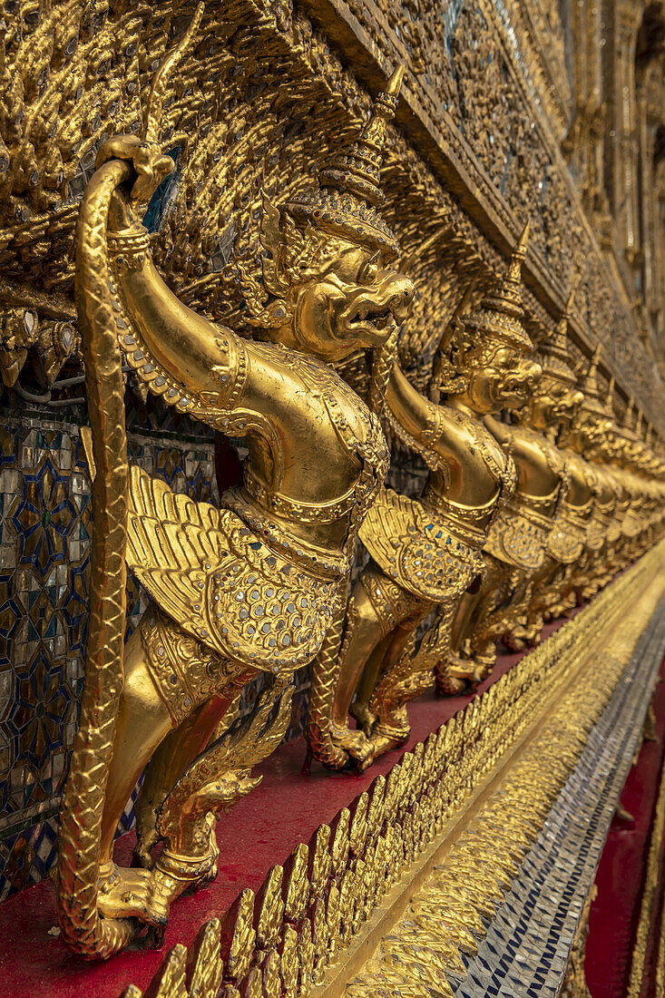 Goldene Skulpturen mythologischer Kreaturen an der Wand des Wat Phra Kaew; Bangkok, Thailand.