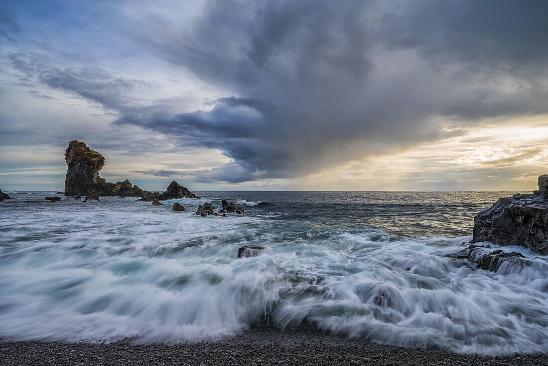 Waves crash against the shoreline of Djupalonssandur beach at sunset, Snaefellsness Peninsula; Iceland