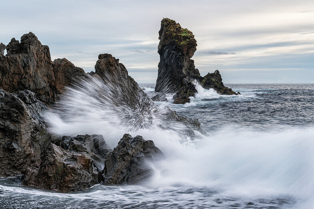 Waves crash against the shoreline of Djupalonssandur beach at sunset, Snaefellsness Peninsula; Iceland