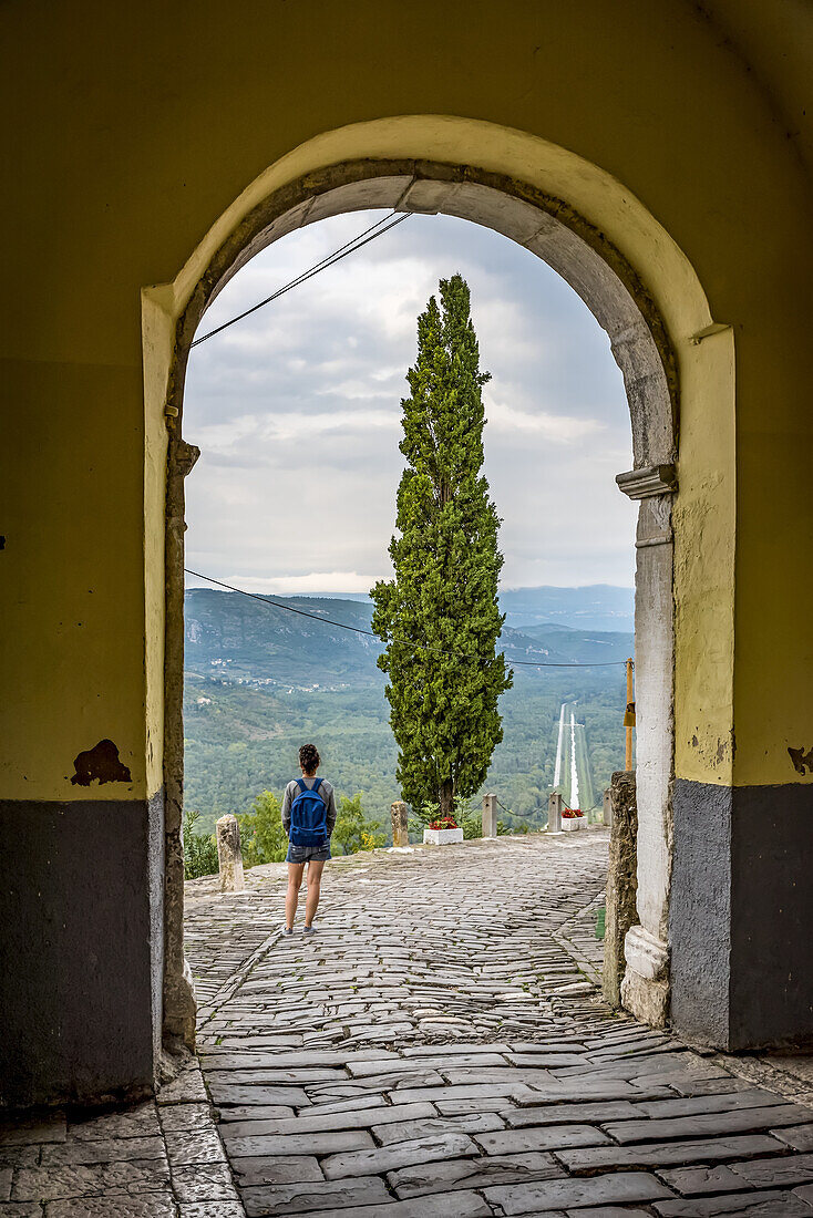 Female tourist looking out from the hilltop medieval town of Motovun; Motovun, Istria, Croatia
