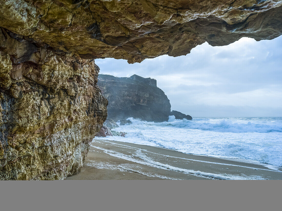 Strand von Nazare mit zerklüfteten Klippen und rauen Wellen; Nazare, Bezirk Leiria, Portugal.