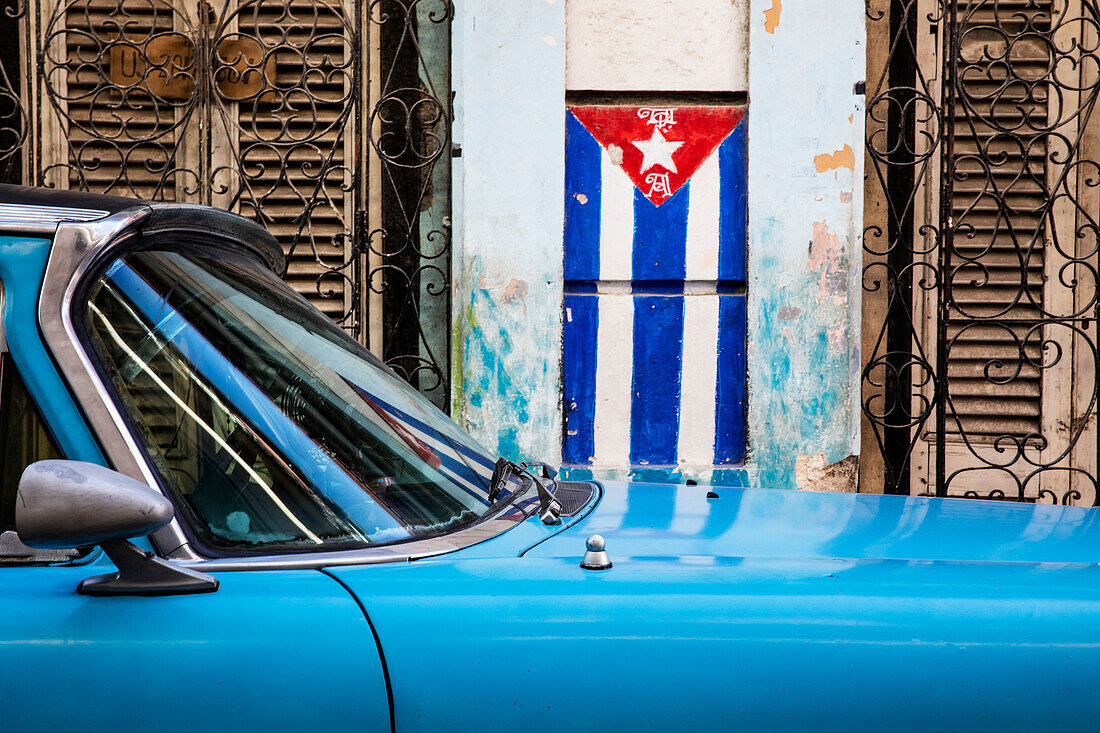 Cuban flag and blue car on the streets of Havana; Havana, Cuba