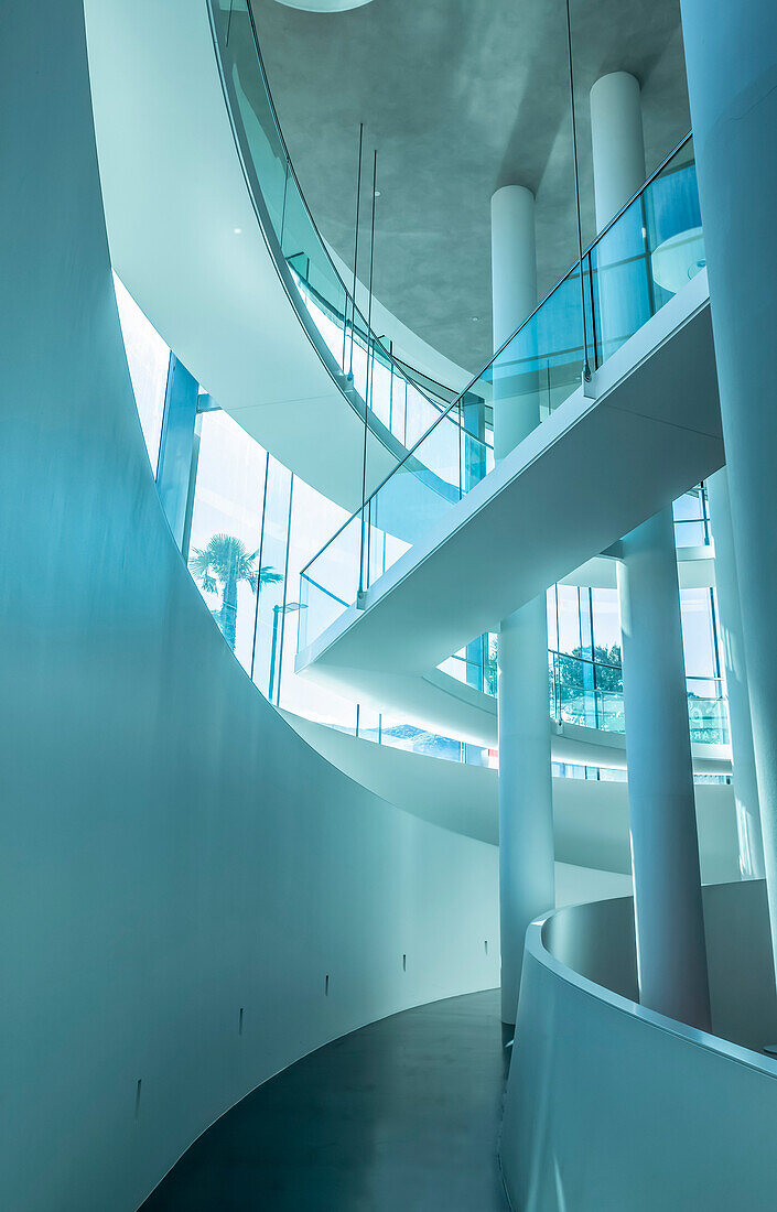 Modern indoor architecture of a corridor with curved white walls, pillars and glass; Lugano, Ticino, Switzerland