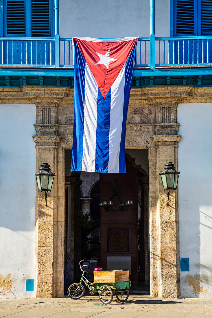 Die kubanische Nationalflagge hängt über dem Eingang zum Palast der Kunsthandwerker (Palacio de la Artesania), Altstadt; Havanna, Kuba.
