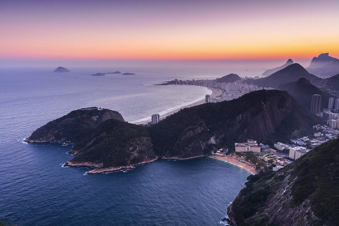 Glühender Sonnenuntergang über dem Atlantischen Ozean und der Küstenlinie mit Hügeln und Stränden von Rio de Janeiro; Rio de Janeiro, Rio de Janeiro, Brasilien