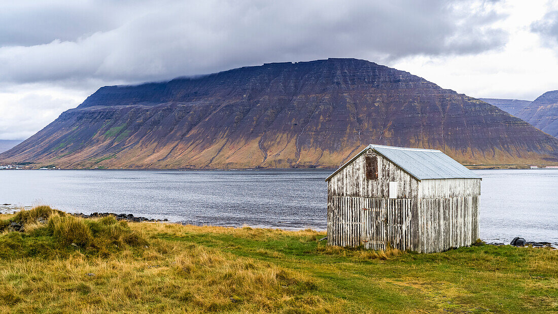 Weathered structure on the water's edge of a fjord in Northwestern Iceland in the municipality of Isafjarourbaer; Isafjarourbaer, Westfjords Region, Iceland