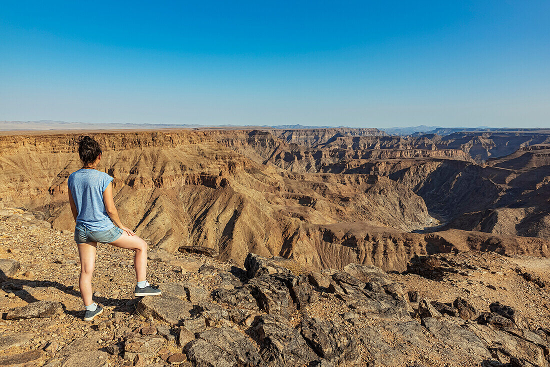 Female tourist standing and looking out over Fish River Canyon; Namibia