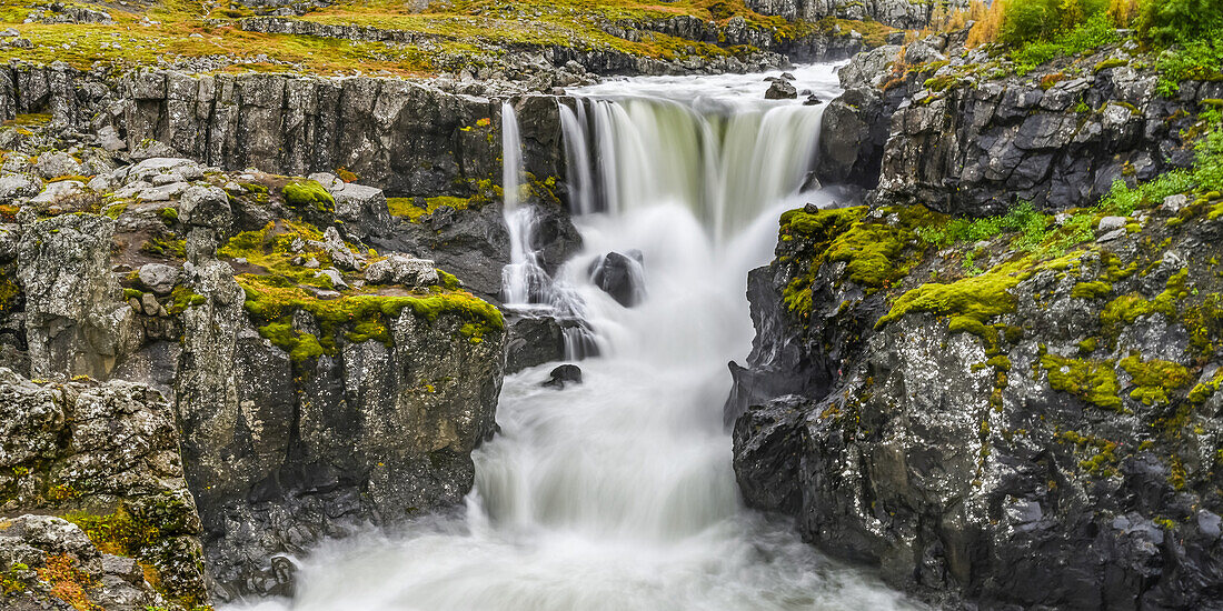 Wasserfall und reißender Fluss in einer zerklüfteten Landschaft in Ostisland; Djupivogur, Ostregion, Island
