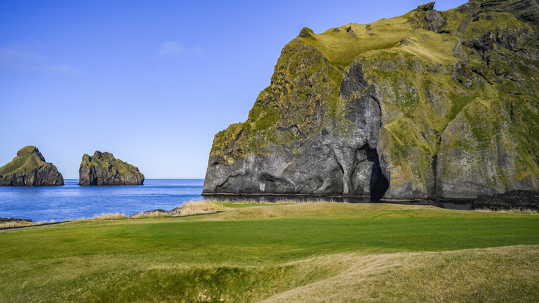 Cave and rock formations along the coastline of Southern Iceland on a bright day; Vestmannaeyjar, Southern Region, Iceland