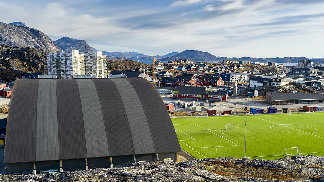 Ein Sportplatz und ein Gebäude mit Blick auf ein Viertel und die Berge; Nuuk, Sermersooq, Grönland
