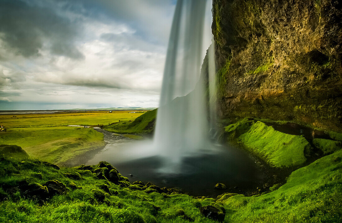 Blick auf einen rauschenden Wasserfall von hinten, Seljalandsfoss; Island