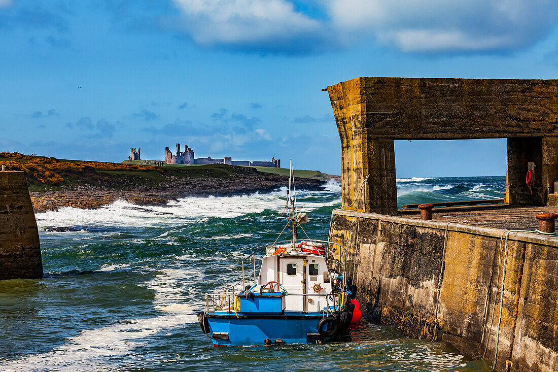 Blick auf Dunstanburgh Castle von einem Pier mit Zementstruktur im Hafen von Craster; Craster, Northumberland, England.