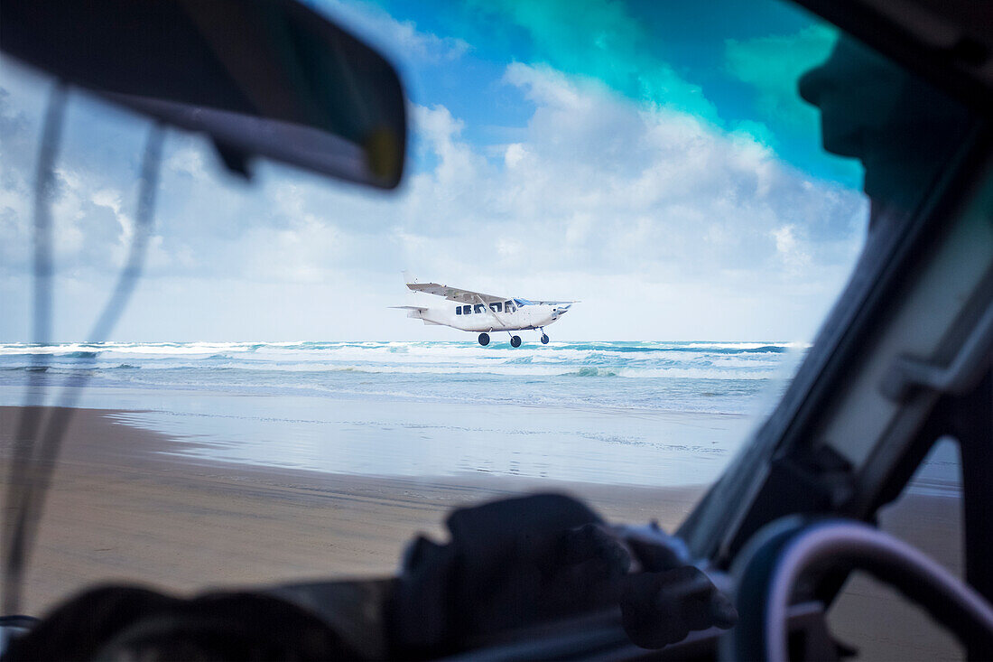 Fraser Island ist die größte reine Sandinsel der Welt. Reisende mieten sich Geländewagen, um die zerklüftete Insel zu erkunden. Ein Wasserflugzeug fliegt entlang der Küste und landet am Strand; Fraser Island, Australien