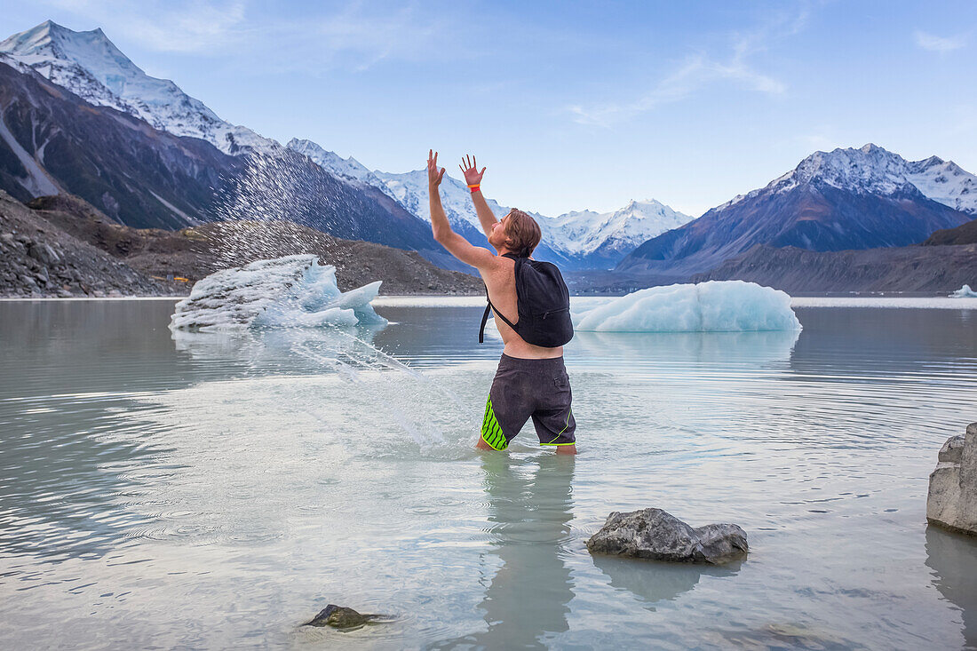 Mann steht und plantscht in den eisigen Gletscherseen des Mount Cook National Park; Canterbury, Neuseeland