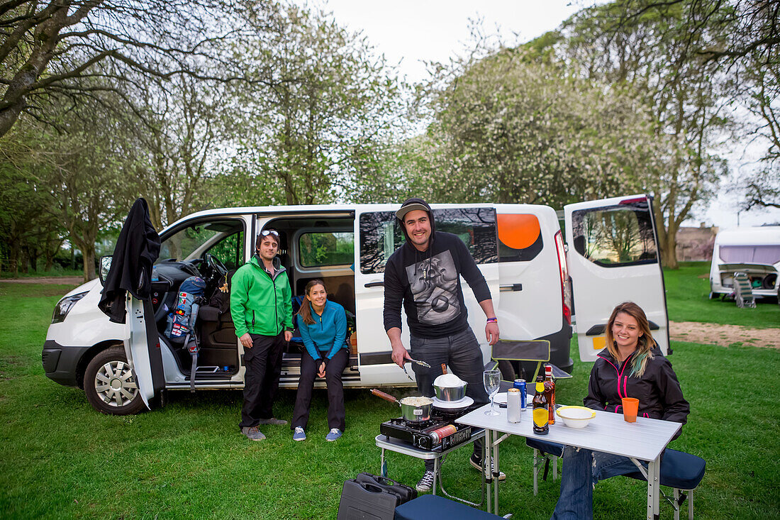 Setting up camp outside of a modified caravan camper; Bourton-on-the-Water,  Gloucestershire, England