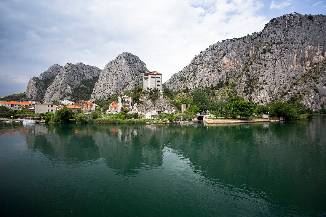 The coastal Croatian city of Omis with rock formations and tranquil water in the harbour; Omis, Splitsko-dalmatinska zupanija, Croatia
