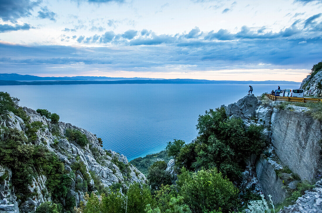 The stunning high altitude cliffside roads along the coastline of Croatia. This road is the Sveti Jure mountain pass that takes you through the Biokovo mountain range. Travelers stop for a sunset photograph; Podgora, Split-Dalmatia County (Splitsko-dalmatinska zupanija), Croatia