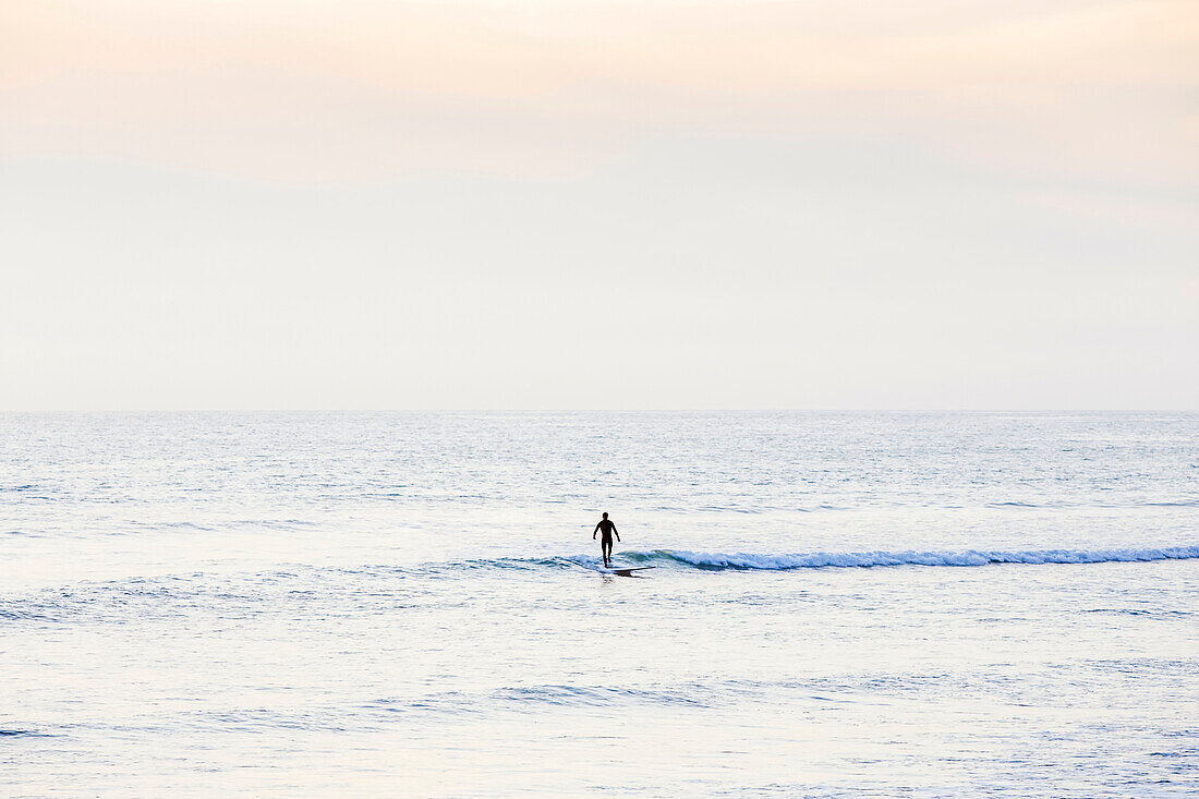 Einsamer Surfer bei Sonnenuntergang am San Onofre State Beach; San Clemente, Kalifornien, Vereinigte Staaten von Amerika