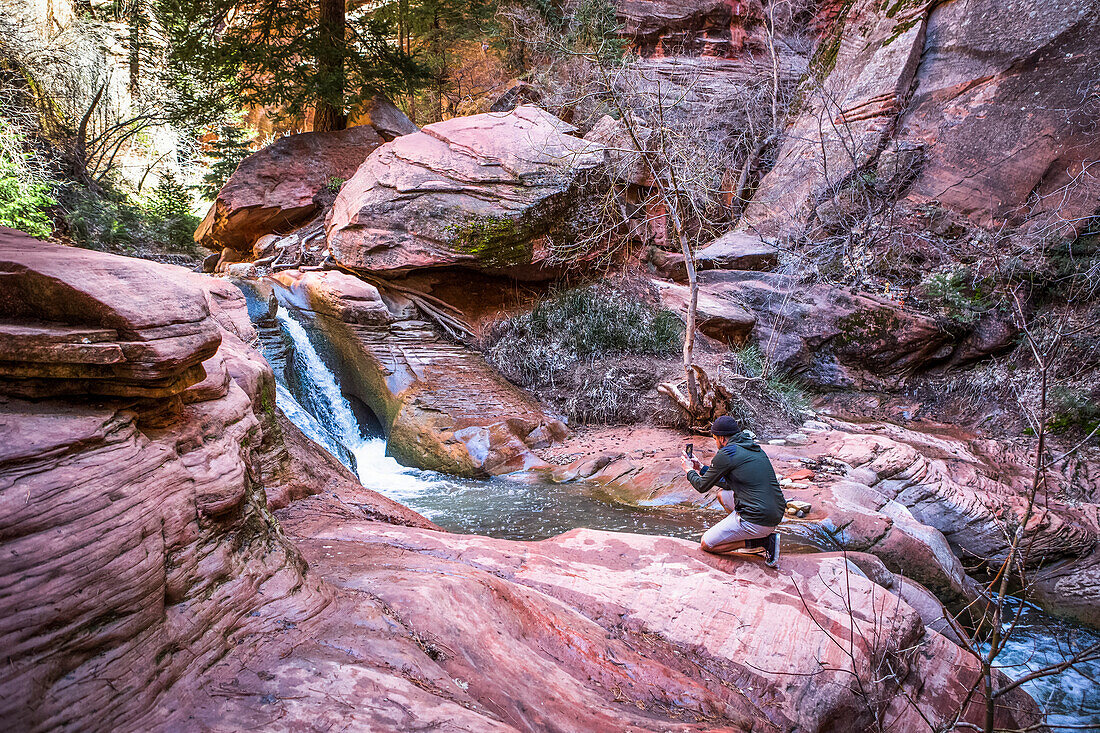 A unique hike through the Kanarraville Canyon Falls in Utah requires hiking through streams and climbing waterfalls in the middle of giant red rock canyons; Kanarraville, Utah, United States
