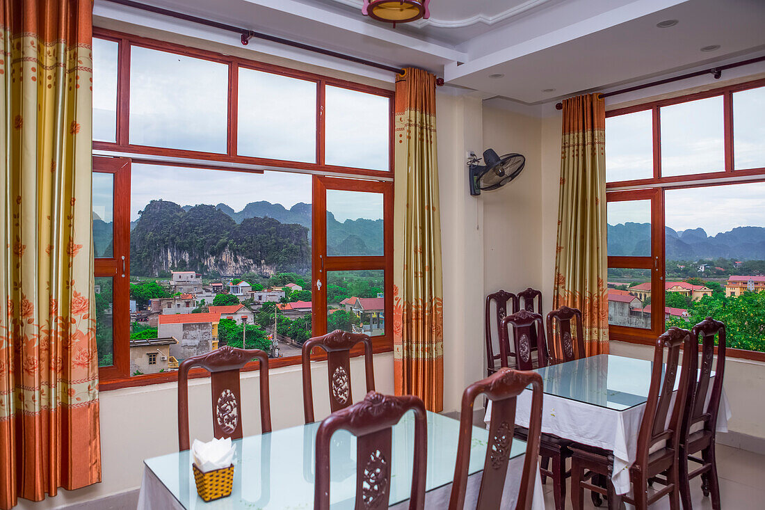 Blick aus dem Fenster eines Restaurants auf die atemberaubende Landschaft von Ninh Binh mit ihren Kalksteinbergen, in denen sich zahlreiche Höhlen und Grotten befinden; Ninh Binh, Vietnam