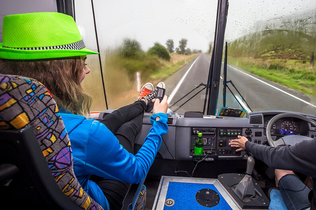 Ein Mädchen sitzt auf dem Vordersitz eines Busses auf der Fahrt durch den Tongariro-Nationalpark in Neuseeland; Manawatu-Wanganui, Neuseeland.