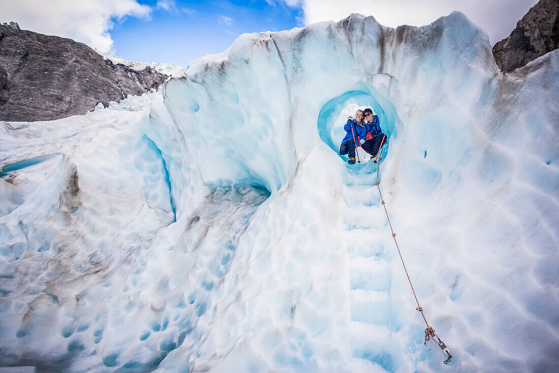 Reisende erkunden Neuseelands berühmten Franz-Josef-Gletscher. Blaues Eis, tiefe Gletscherspalten, Höhlen und Tunnel kennzeichnen das sich ständig verändernde Eis; Westküste, Neuseeland