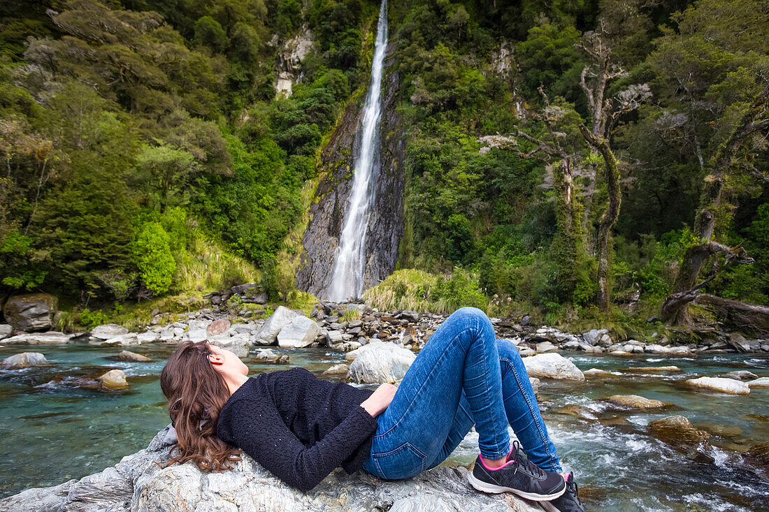 Tourist explores a random waterfall in a remote region of New Zealand's South Island; New Zealand