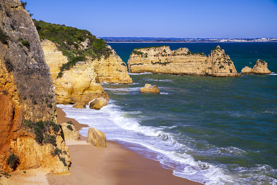 Die Brandung des Atlantiks am Dona Ana Strand mit seiner felsigen Sandsteinküste und den Felsen entlang der berühmten Algarveküste; Praia da Dona Ana, Lagos, Algarve Region, Portugal