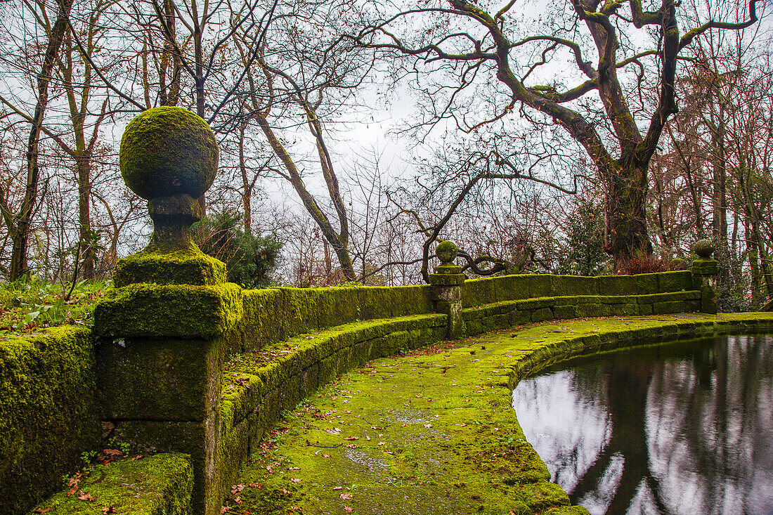 Moss covered stone walkway around a tranquil pond at the Gardens of the Santa Marinha da Costa Monastery behind Pousada Mosteiro de Guimaraes; Guimaraes, Braga District, Portugal