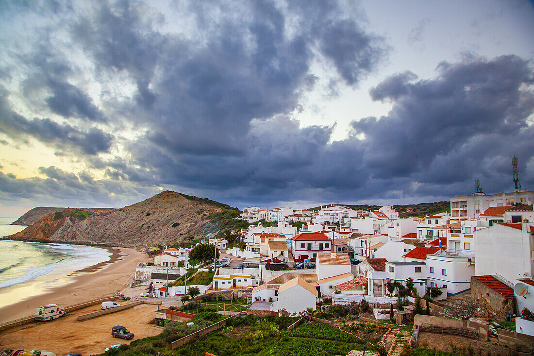 Dramatic grey cloud formation swirling above the traditional fishing village of Burgau in the municipality of Vila do Bispo in the Western Region of Algarve at dusk; Burgau, Algarve, Portugal