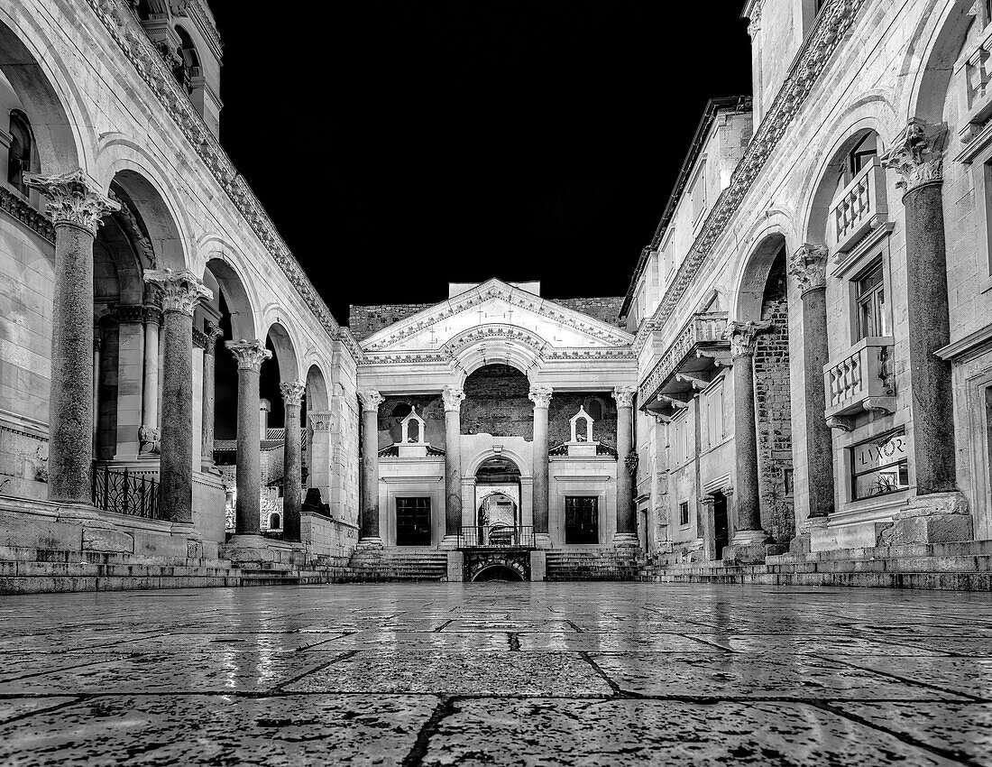 Palast des römischen Kaisers Diokletian, zeigt den Hauptplatz des Palastes, Peristil, nachts beleuchtet, mit dem Mausoleum des Diokletian, das in eine Kathedrale umgewandelt wurde, die Kathedrale des Heiligen Domnius, die von zwei Kolonnaden begrenzt wird; Split, Kroatien.