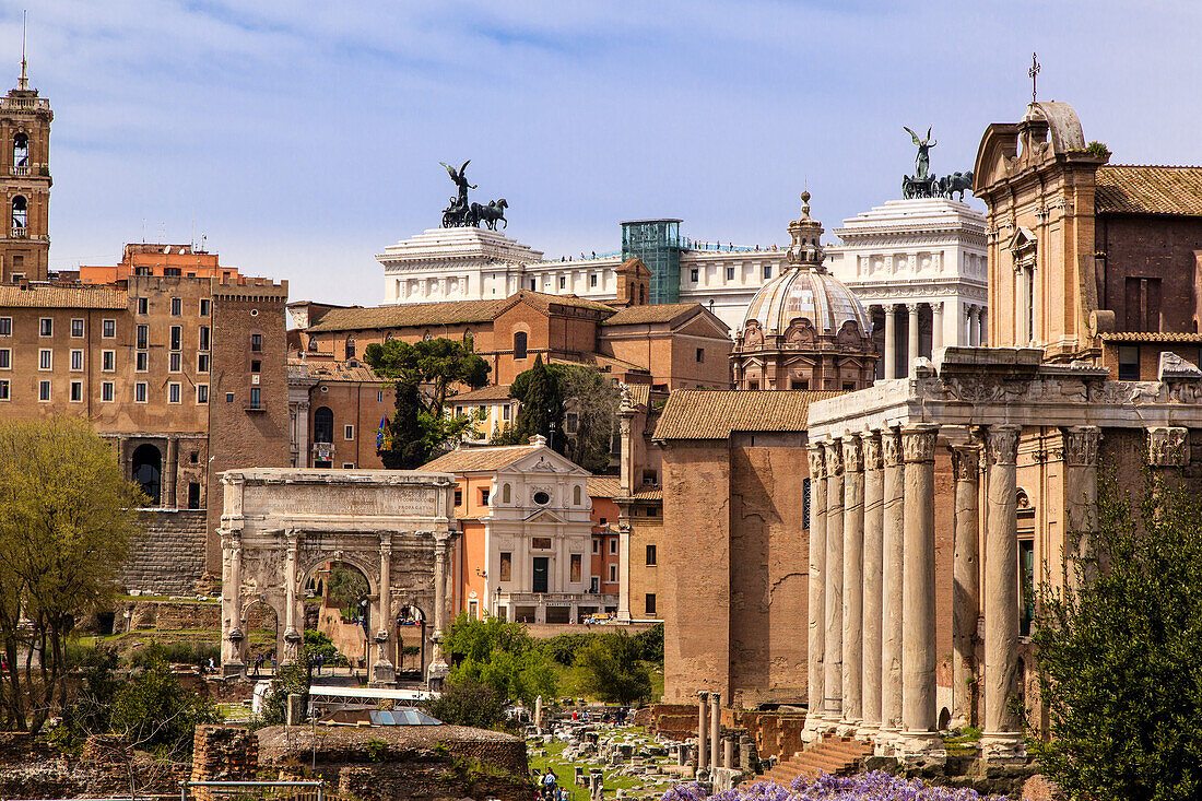 Überblick über das Forum Romanum mit dem Septimius-Severus-Bogen, der Kuppel der Kirche Santi Luca e Martina, der Kurie und dem Tempel des Antoninus und der Faustina (Kirche von San Lorenzo in Miranda). Im Hintergrund sind auch die weiße Marmorkuppel und die Bronzeskulpturen des Denkmals von Vittorio Emanuele II. auf dem Palatinhügel zu sehen; Rom, Latium, Italien