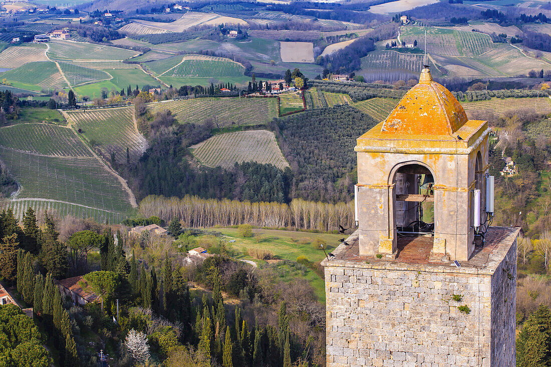 Spitze eines der vielen Glockentürme in der mittelalterlichen Hügelstadt San Gimignano mit Blick auf die toskanische Landschaft; San Gimignano, Provinz Siena, Toskana, Italien
