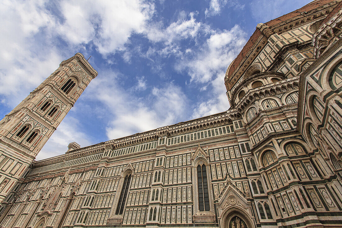 Der berühmte Dom von Florenz (Il Duomo di Firenze), ein reich verzierter gotischer Bau aus grünem, weißem und rosafarbenem Marmor vor einem wolkenverhangenen blauen Himmel; Florenz, Toskana, Italien.