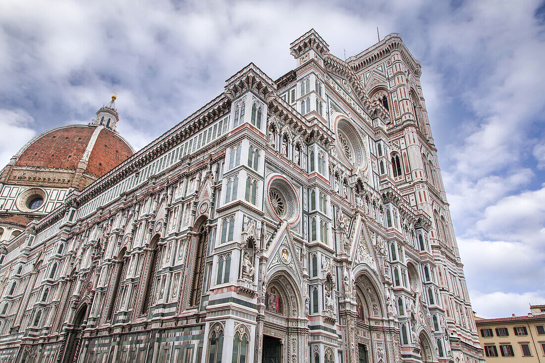 Der berühmte Dom von Florenz (Il Duomo di Firenze), ein reich verzierter gotischer Bau aus grünem, weißem und rosa Marmor vor einem wolkenverhangenen blauen Himmel; Florenz, Toskana, Italien.