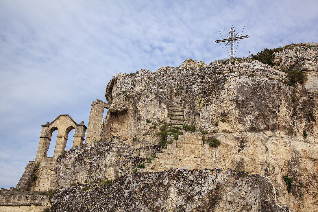 Christliches Kreuz und Ruinen auf einem felsigen Berggipfel; Matera, Basilikata, Italien