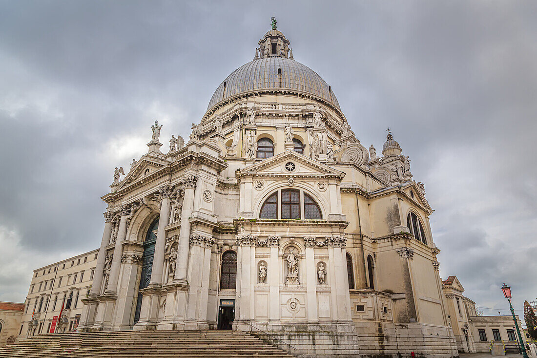 Die prächtige Basilica di Santa Maria della Salute in der Nähe des Eingangs zum Canal Grande im Stadtteil Punta della Dogna im Dorsoduro vor einem grauen, bewölkten Himmel; Venedig, Venezia, Italien.